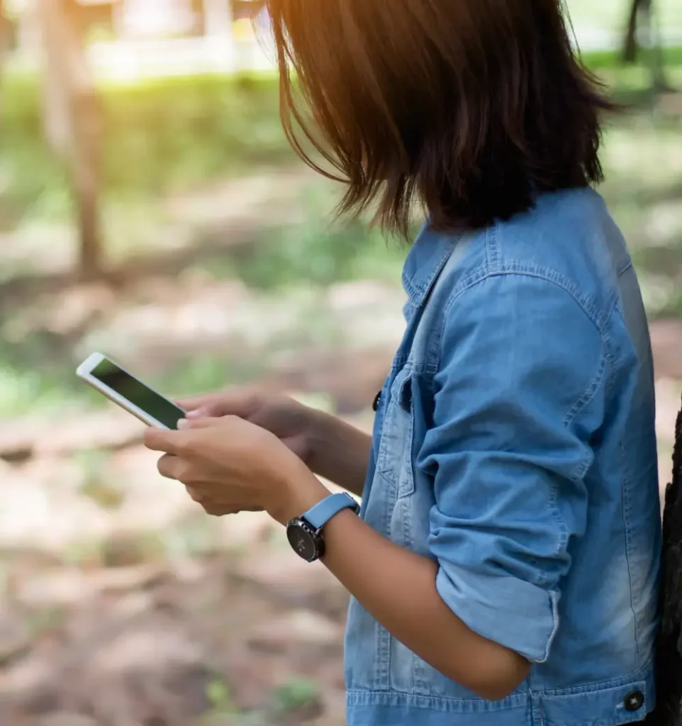 A short haired person wearing denim jacket using his phone