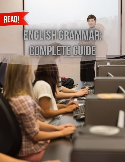 Teacher standing in front of projection screen facing bunch of students teaching grammar