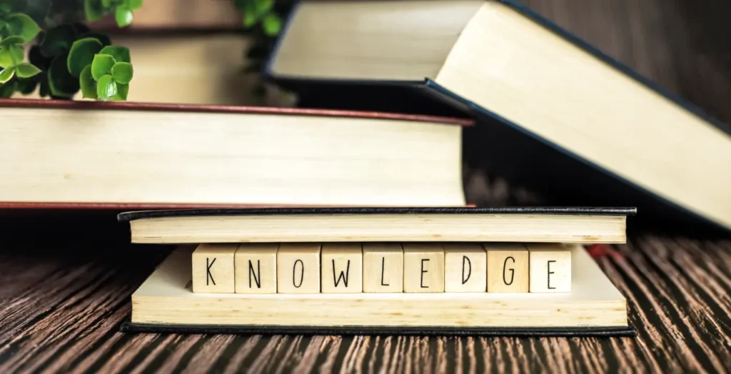 Books stacking with wood alphabet "KNOWLEDGE"